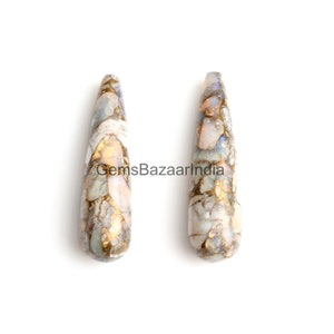 May include: Two teardrop-shaped opal gemstone pendants with a white, gold, and iridescent finish. The pendants are approximately 2 inches long.