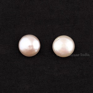 May include: Two round, white pearls on a black background.