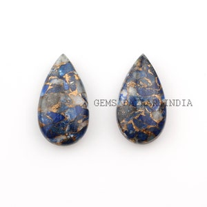 Puede incluir: Dos cabujones de piedra preciosa en forma de lágrima con un patrón de mármol azul, dorado y blanco. Los cabujones miden aproximadamente 2,5 cm de largo y 1,5 cm de ancho. GEMS BAZAAR INDIA está impreso en el fondo.
