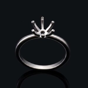 Puede incluir: Un engaste de anillo plateado con un diseño de seis puntas para sujetar una gema. El anillo tiene una banda pulida y redondeada y un engaste detallado, ideal para un anillo de compromiso personalizado.