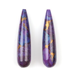 May include: Two teardrop-shaped purple and gold gemstone beads. The beads have a marbled pattern with gold flecks throughout.