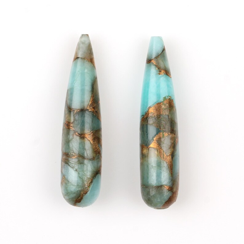 May include: Two teardrop-shaped turquoise and gold gemstone beads. The beads have a marbled pattern of turquoise and gold.