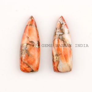 May include: Two orange, white, and gold marbled gemstone cabochons in a teardrop shape.  The cabochons are polished and have a smooth, glossy finish.  Gems Bazaar India.