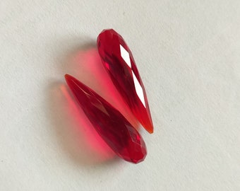 Può includere: Due perline di cristallo rosse a forma di lacrima con bordi sfaccettati.