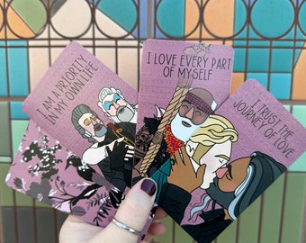 May include: Three pink affirmation cards with illustrated people and text. The cards read "I am a priority in my own life", "I love every part of myself", and "I trust the journey of love".