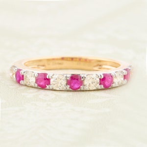 May include: A gold band ring with alternating ruby and diamond stones. The ring is set in a white metal.