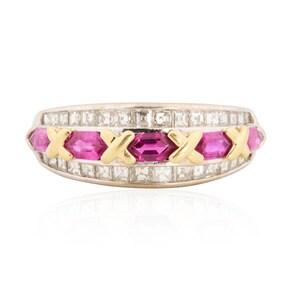 May include: A gold and silver ring with a row of pink gemstones and gold X-shaped accents. The ring is encrusted with small, square-cut clear stones. The gemstones are a vibrant pink color, and the ring has a polished finish.
