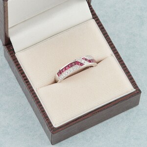 May include: A white gold ring with a band of alternating red rubies and white diamonds.