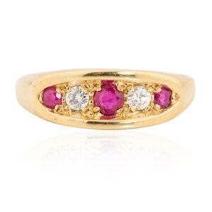 Könnte beinhalten: Ein goldener Ring mit fünf Edelsteinen. Der Ring hat ein abgerundetes Band und ist mit drei leuchtend roten Rubinen und zwei funkelnden weißen Diamanten besetzt. Die Edelsteine sind in einer Reihe angeordnet und schaffen ein klassisches und elegantes Design.