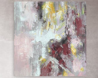 May include: Abstract painting in shades of pink, gray, and yellow hanging on a wall in a modern loft style room with a wooden table and white metal chairs.