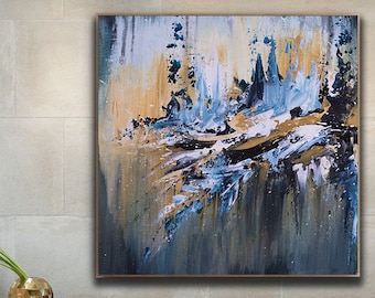 May include: Abstract painting with blue, gold, and white paint strokes on a canvas. The painting is hanging on a wall in a modern living room with a gray couch and a white bed.