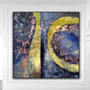 May include: Abstract painting with gold, blue, and pink colors. The painting features a large circle with a smaller circle inside. The background is a textured blue.