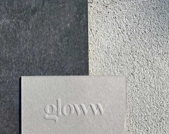May include: A close-up of a grey card with the word "gloWW" embossed in a white font.