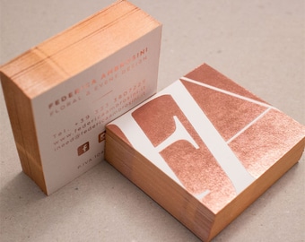 May include: A stack of business cards with a rose gold metallic finish. The text on the card reads "Federica Ambrosini Floral & Event Design" with contact information and social media icons.