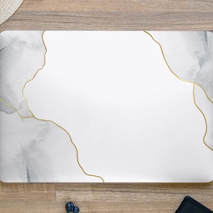May include: White laptop cover with a marble design and gold accents.