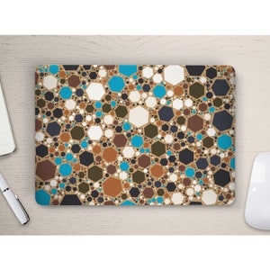 May include: Rectangular laptop sleeve with a repeating geometric pattern of various sized hexagons in shades of brown, blue, white, and black. The sleeve is on a light wood surface, with a pen, notebook, and mouse visible.
