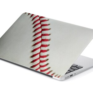 May include: A laptop computer with a white baseball skin on the lid. The baseball skin has red stitching.