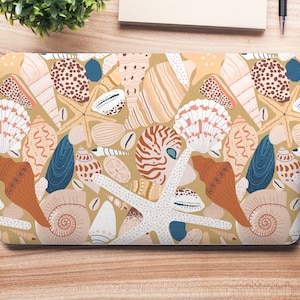 May include: A laptop skin with a colorful pattern of seashells and starfish on a beige background.