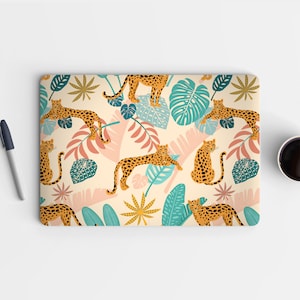 May include: A laptop skin with a repeating pattern of leopards and tropical leaves in shades of green, blue, pink, and yellow on a cream background.
