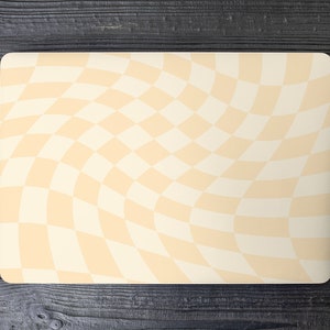 Puede incluir: Un ordenador portátil con una piel de patrón a cuadros en tonos crema y blanco. La piel tiene un efecto ondulado y distorsionado.