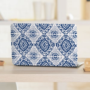 Puede incluir: Una funda para portátil blanca con un patrón geométrico azul y blanco. El patrón presenta diseños intrincados con forma de diamante.