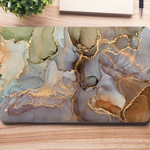 Peut inclure: Une peau d'ordinateur portable avec un design marbré présentant des tourbillons abstraits de gris, de brun et d'or. Le design ressemble à une peinture à l'aquarelle.