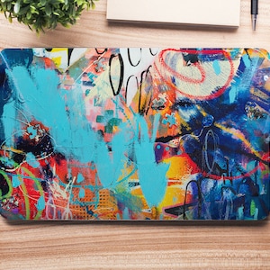 May include: Abstract laptop skin with a colorful design featuring blue, red, yellow, and orange paint splatters and brushstrokes. The design has a graffiti-style aesthetic.