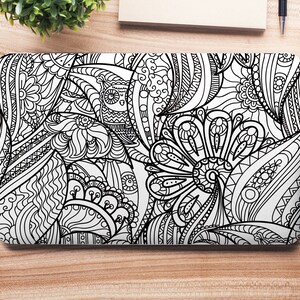 May include: A black and white laptop skin with a detailed, intricate pattern of flowers, leaves, and swirls. The design is reminiscent of a coloring book page.