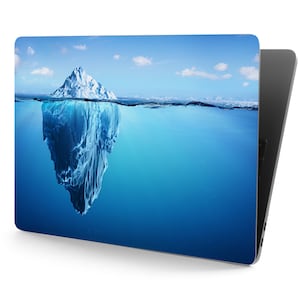 Puede incluir: Un gran iceberg parcialmente sumergido en agua azul. El iceberg es blanco con un tono azul y tiene una forma irregular y dentada. El agua es clara y azul, con una línea blanca en la superficie.