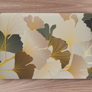 May include: A laptop skin with a pattern of gold, brown, and green ginkgo leaves on a light gray background.