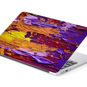 May include: A laptop computer with a colorful abstract design on the lid. The design features shades of purple, yellow, orange, and red.