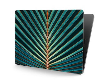 May include: A close-up of a teal green palm leaf with a symmetrical pattern of lines radiating from the centre.