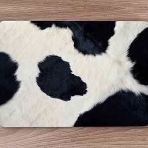 May include: Black and white cowhide pattern with a close-up view of the fur texture.