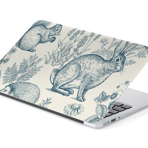 Op de afbeelding: Een laptop-huid met een crèmekleurige achtergrond en een blauw en wit patroon van een eekhoorn, een konijn, een egel en verschillende planten.
