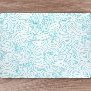 Puede incluir: Una piel de portátil blanca con un patrón de olas azules. Las olas están dibujadas en un estilo abstracto y en espiral.