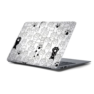 Op de afbeelding: Een laptop met een wit en zwart ontwerp met een patroon van kattenpootjes en katten. De laptop is gesloten en het ontwerp bevindt zich op de deksel.