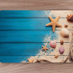 May include: A blue wooden background with a white sandy texture on the right side. The sand is sprinkled with seashells and starfish.