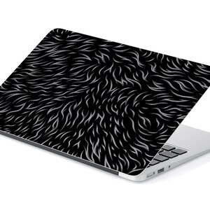 May include: A silver laptop with a black and white fur pattern on the lid. The laptop is closed and sitting on a white surface.
