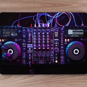 May include: A black DJ mixer with two turntables, illuminated with purple and blue lights. The mixer has a variety of knobs, buttons, and sliders. There are headphones on the left turntable.