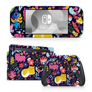 May include: A Nintendo Switch console and controllers with a floral and cat-themed skin. The skin features a dark blue background with colorful flowers, leaves, and cartoon cats. The console has the words "Nintendo Switch" on the screen.