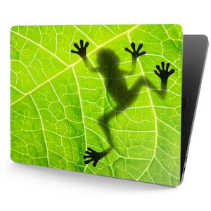 May include: A laptop skin with a green leaf design featuring a silhouette of a frog.