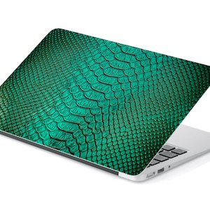 Op de afbeelding: Een laptop met een groen slangenhuidpatroon op de deksel. De laptop is gesloten en de deksel is open om het patroon te laten zien.