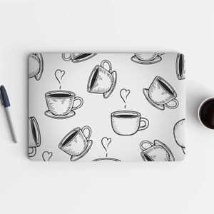 May include: A laptop computer with a white background and a black and white doodle pattern of coffee cups. The pattern is repeated across the entire surface of the laptop.