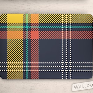 May include: A laptop skin with a plaid pattern in shades of yellow, red, teal, and white on a dark blue background. The skin is designed to fit a laptop computer.