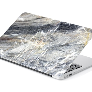 May include: A laptop computer with a gray and white marble design on the lid. The laptop is closed and sitting on a white surface.