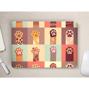 Op de afbeelding: Een laptop skin met een kleurrijk patroon van kattenpootjes. De pootjes zijn in verschillende kleuren en patronen, waaronder bruin, oranje, geel en zwart. De achtergrond is lichtblauw, roze en geel.