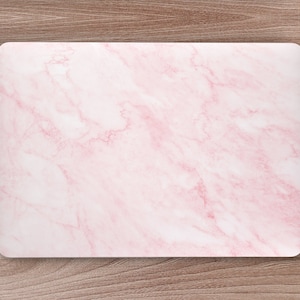May include: A pink marble laptop skin with a white background. The skin is designed to fit a laptop computer.