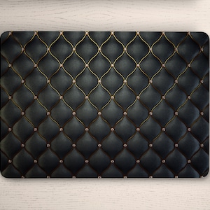 Könnte beinhalten: Eine schwarze Laptop-Haut mit einem gesteppten, rautenförmigen Muster und goldenen Nähten. Die Haut hat einen dezenten Glanz und ist mit kleinen, klaren Strasssteinen verziert.