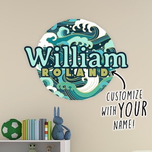 May include: A blue and white circular wall decal with a wave pattern and the name "William Roland" in a stylised font. The text "Customize with your name!" is also included in the image.