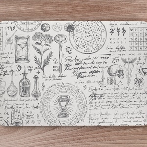 May include: A black and white illustration of a variety of occult symbols, including a skull, a chalice, a key, an hourglass, and a pentagram. The symbols are surrounded by handwritten text and other decorative elements.